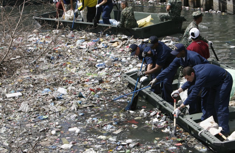 U.S. servicemen remove garbage clogging a small river during a clean-up activity in Manila (photo credit: REUTERS)