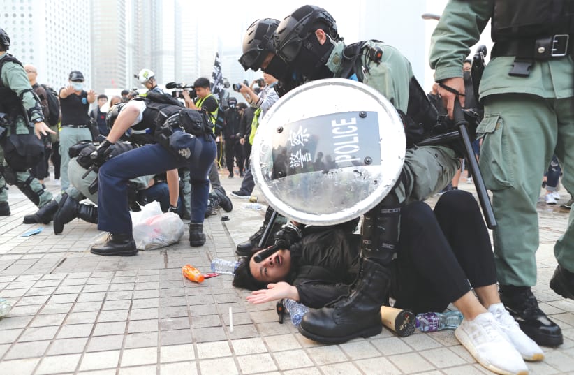 POLICE ARREST a protester after a Chinese flag was removed from a flag pole at a rally in Hong Kong yesterday in support of Xinjiang Uighurs’ human rights. (photo credit: REUTERS/LUCY NICHOLSON)