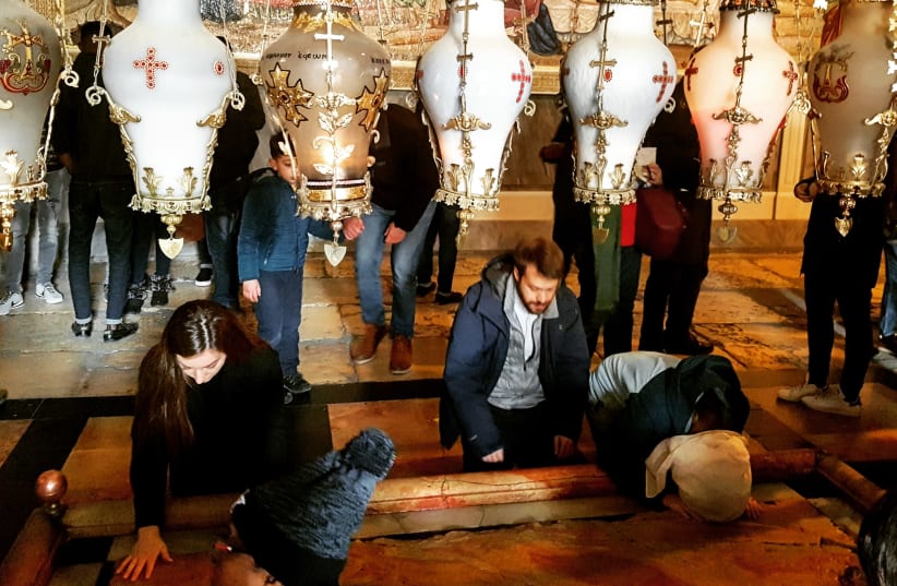 Christian visitors pray at the Stone of Unction in the Church of the Holy Sepulchre on Christmas day. (photo credit: ILANIT CHERNICK)