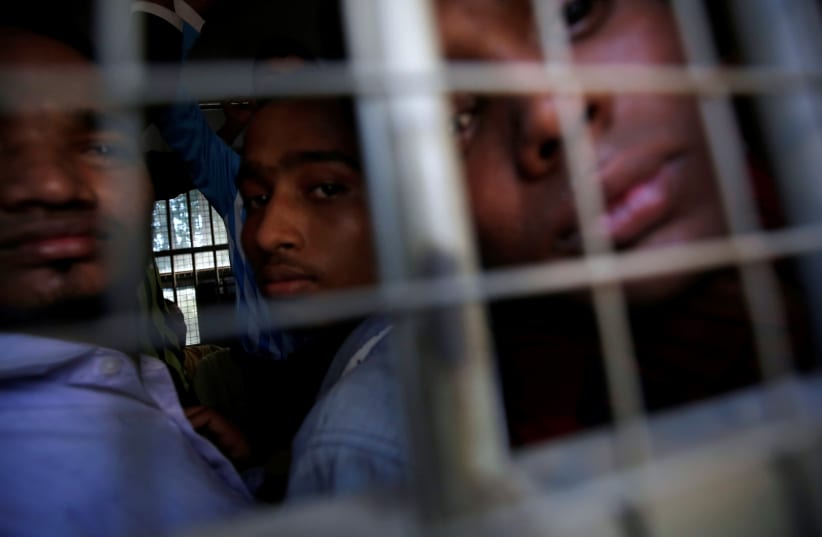 Rohingya Muslim men look out from inside a police vehicle, as they are transported from a court hearing on charges of illegally travelling without proper documents, in Pathein, Ayeyarwady, Myanmar December 20, 2019 (photo credit: ANN WANG/REUTERS)