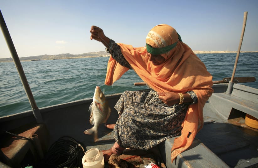 Hava Arbabi holds up fish in her boat near Hengam Island southeast of Tehran, Iran (photo credit: REUTERS/MORTEZA NIKOUBAZL)