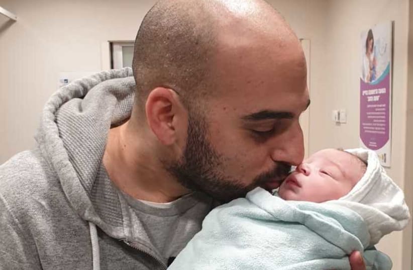 Adam Ben-Naim kissing his newborn son (photo credit: Courtesy)