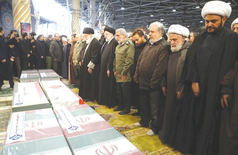 Iran's Supreme leader Ayatollah Ali Khamenei prays near the coffins of Iranian Major Qassem Soleimani and Iraqi militia commandr Abu Mahdi al-Muhandis who were killed in last wee;s US air strike at Baghdad airport.  (photo credit: REUTERS)