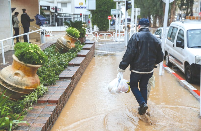 A MAN TRUDGES through puddles in Nahariya yesterday – Was the week’s saber-rattling between the US and Iran, with Israel in the middle, even on his mind? (photo credit: DAVID COHEN/FLASH 90)