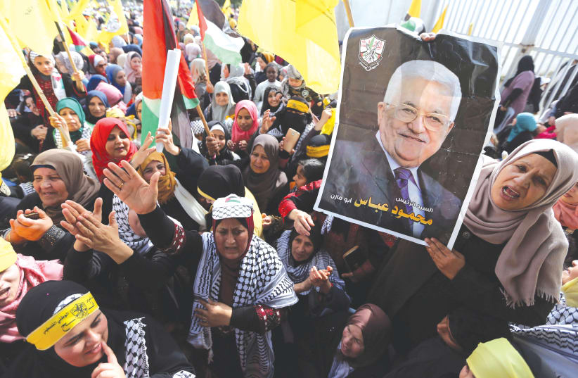 A WOMAN holds a picture of PA President Mahmoud Abbas during a rally earlier this month in Gaza City marking the 55th anniversary of Fatah’s founding.  (photo credit: IBRAHEEM ABU MUSTAFA / REUTERS)