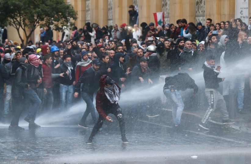 Demonstrators are hit by water canon during a protest against a ruling elite accused of steering Lebanon towards economic crisis in Beirut, Lebanon January 18, 2020. (photo credit: REUTERS)