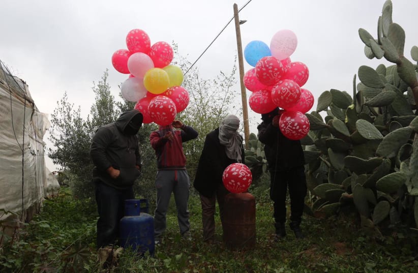 Masked Palestinians release incendiary balloons near Khan Yunis in the Gaza Strip   (photo credit: MAJDI FATHI/TPS)