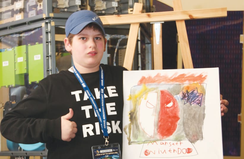 A young participant in 'Space City' holds a drawing he made. (photo credit: MICHAEL VINERSKI)