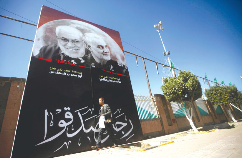 A MAN passes next to a billboard with posters of Iranian Major-General Qasem Soleimani, head of the elite Quds Force, and Iraqi militia commander Abu Mahdi al-Muhandis. (photo credit: REUTERS)