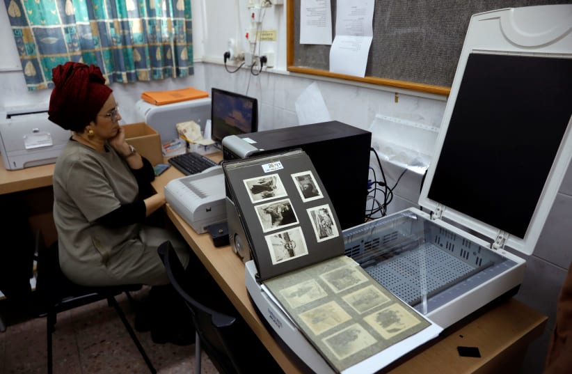 An employee demonstrates the scanning process of photographs during an interview with Reuters at the offices of Shem Olam Holocaust Memorial Centre in Kfar Haroeh, Israel January 14, 2020 (photo credit: RONEN ZVULUN/REUTERS)