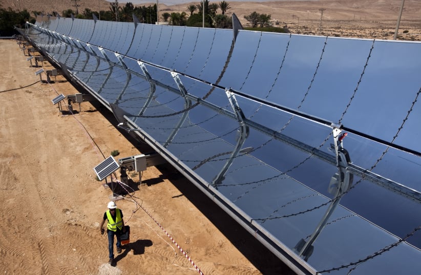 A worker walks next to parabolic mirrors at the research site of solar power company Brenmiller Energy near Dimona (photo credit: NIR ELIAS / REUTERS)