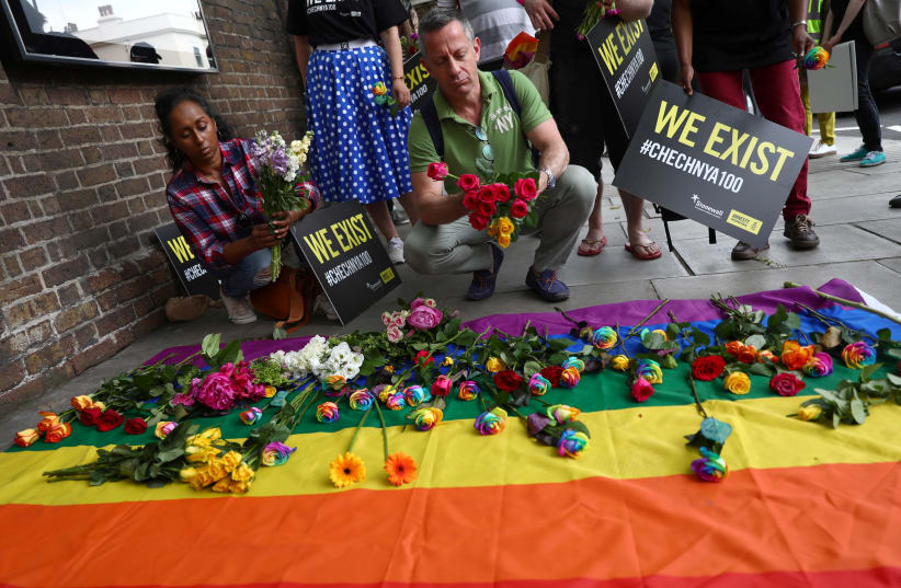 Campaigners place flowers on a multicoloured flag as they protest for LGBT rights in Chechnya outside the Russian embassy in London, Britain June 2, 2017 (photo credit: REUTERS/NEIL HALL)