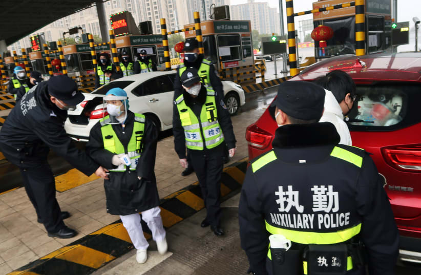 Police officers wearing masks check the boot of a car for smuggled wild animals following the outbreak of a new coronavirus, at an expressway toll station on the eve of the Chinese Lunar New Year celebrations, in Xianning (photo credit: REUTERS)