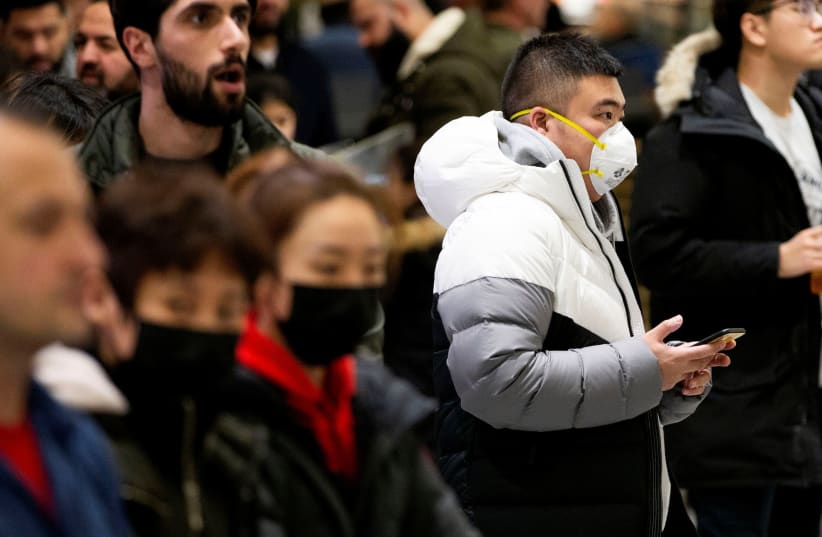 People waiting for passengers wear masks at Pearson airport arrivals, shortly after Toronto Public Health received notification of Canada's first presumptive confirmed case of coronavirus, in Toronto, Ontario, Canada January 25, 2020 (photo credit: REUTERS/CARLOS OSORIO)