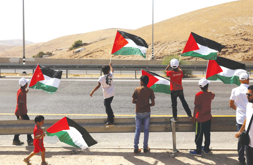WHO WILL rule this? Palestinians wave flags at traffic on Highway 1 leading to the Dead Sea (photo credit: REUTERS)