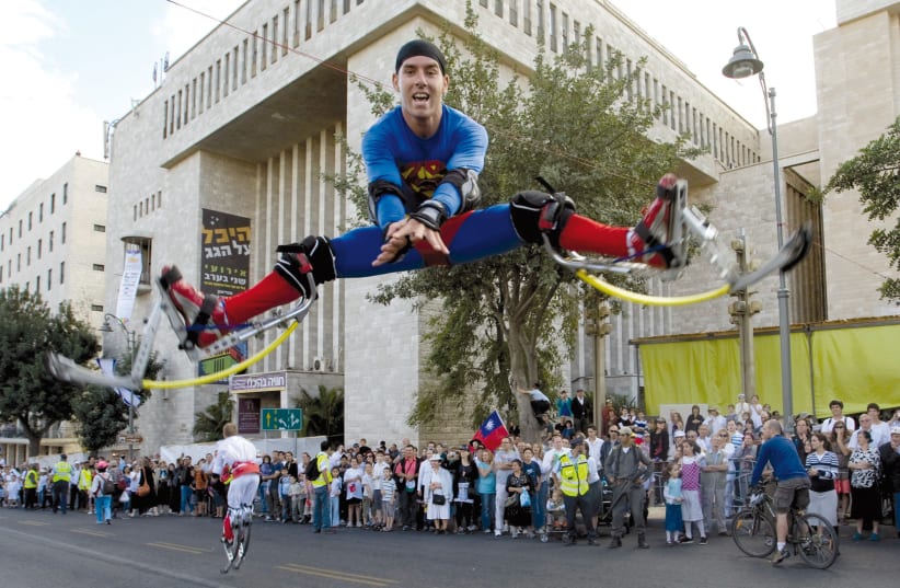 A marcher dressed as Superman performs opposite the Great Synagogue in the annual Jerusalem parade during the festival of Sukkot  (photo credit: REUTERS)