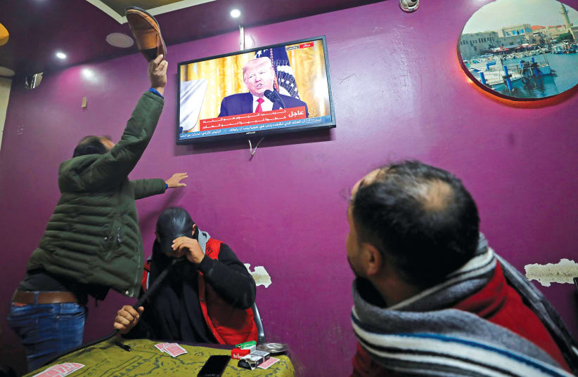 A PALESTINIAN man in a coffee shop in Hebron uses his shoe to hit a television screen broadcasting the announcement of the peace plan by US President Donald Trump on Tuesday (photo credit: REUTERS/MUSSA QAWASMA)