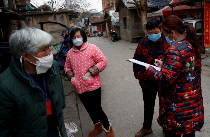 Members of a neighbourhood committee register locals and ask about therr travel history in Jiujiang, Jiangxi province, China, as the country is hit by an outbreak of novel coronavirus. February 2, 2020 (photo credit: REUTERS/THOMAS PETER)