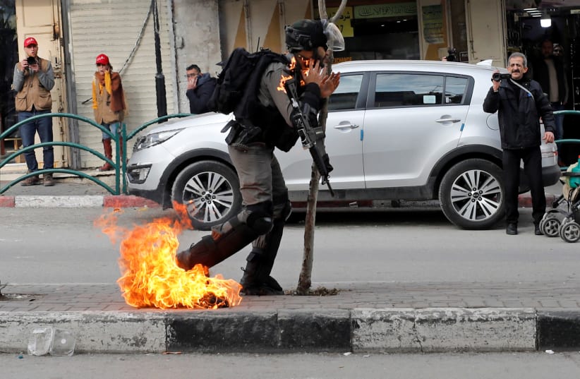 Israeli border policeman is on fire as he is hit with a molotov cocktail thrown by Palestinian demonstrators, Feb. 3, 2020 (photo credit: MUSSA ISSA QAWASMA/REUTERS)