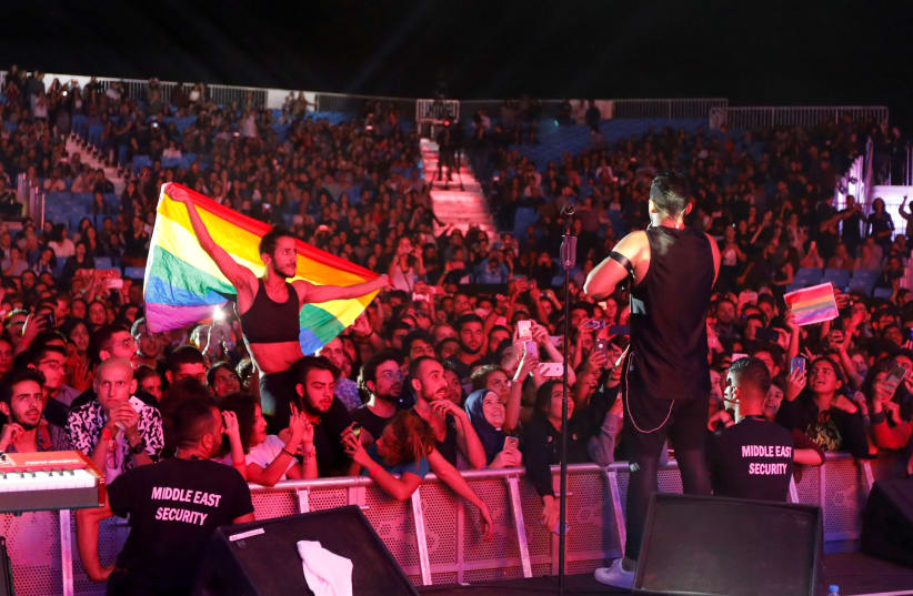 FILE PHOTO: A fan of Lebanese alternative rock band Mashrou' Leila holds a rainbow flag during their concert at the Ehdeniyat International Festival in Ehden town, Lebanon August 12, 2017. Picture taken August 12, 2017 (photo credit: REUTERS/JAMAL SAIDI/FILE PHOTO)