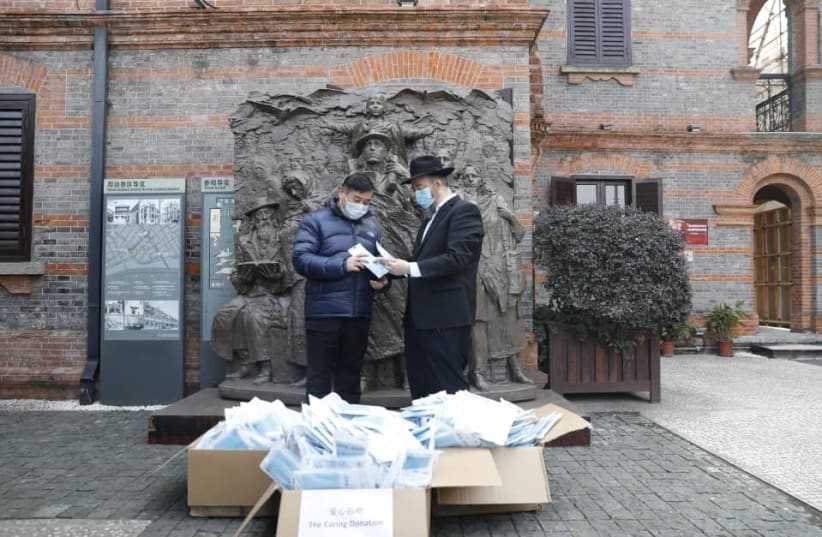 Chabad emissaries distributing masks in front of the monument remembering Jewish refugees who found shelter in Shanghai in the area known as the Hongkou ghetto (photo credit: COURTESY OF CHABAD SHANGHAI)