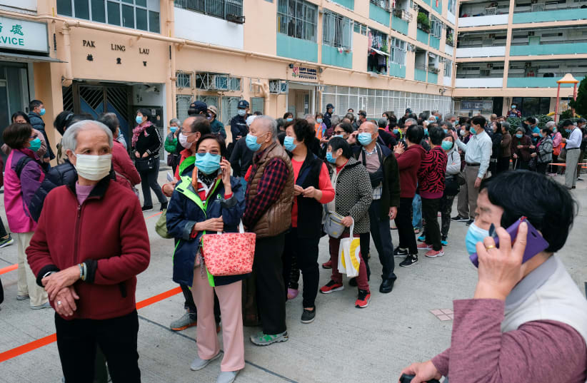 Elderly people queue up for free surgical masks from a convenience store, following the outbreak of a new coronavirus, in Hong Kong, China February 7, 2020. (photo credit: REUTERS/TYRONE SIU)