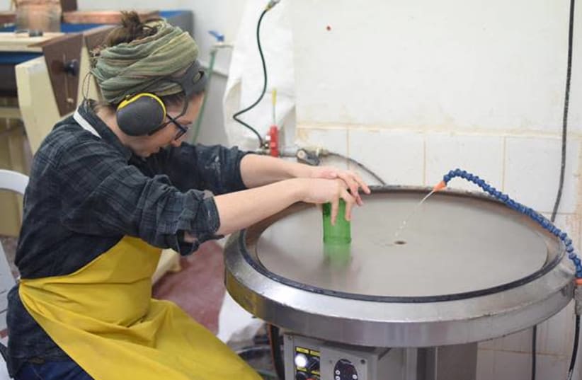 Stephanie Jude, Student in the Department of Ceramics and Glass Design at Bezalel Academy, smoothing the sharp glass edges using a horizontal grinding wheel at the “CupAthon” event, ahead of Tu Bishvat 2020. (photo credit: NOA GOLDBLAT)