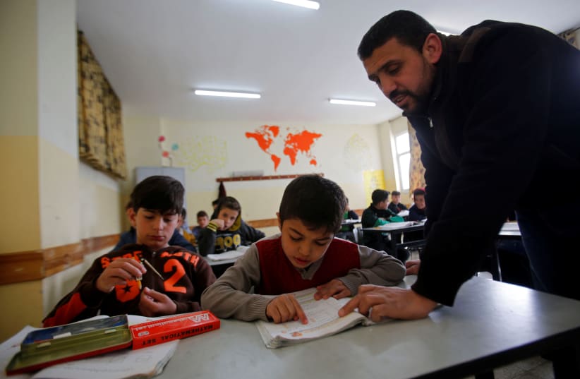 Palestinian boy Zain Idrees attends a lesson inside a classroom in a school, in Hebron, in the West Bank April 25, 2019 (photo credit: REUTERS/MUSSA QAWASMA)