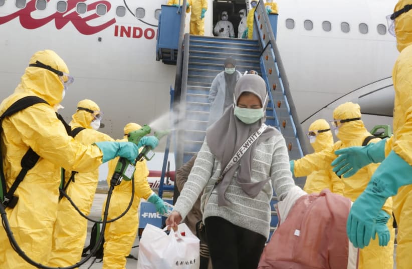 MEDICAL OFFICERS spray Indonesian nationals with antiseptic as they arrive from Wuhan, China’s center of the coronavirus epidemic, before transferring them to be quarantined, in Indonesia on February 2. (photo credit: REUTERS)