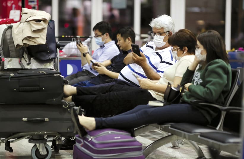 TRAVELLERS, WEARING masks as a precautionary measure to avoid contracting coronavirus, are seen at Guarulhos International Airport in Guarulhos, Sao Paulo state, Brazil.  (photo credit: REUTERS)