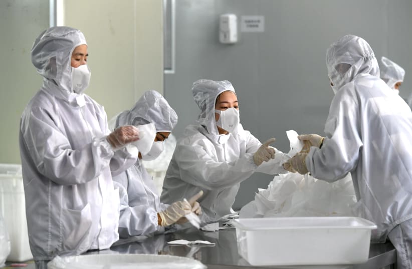Employees work on a production line manufacturing face masks at a factory, as the country is hit by an outbreak of the novel coronavirus, in Fuzhou, Fujian province, China February 15, 2020 (photo credit: CNSPHOTO VIA REUTERS)