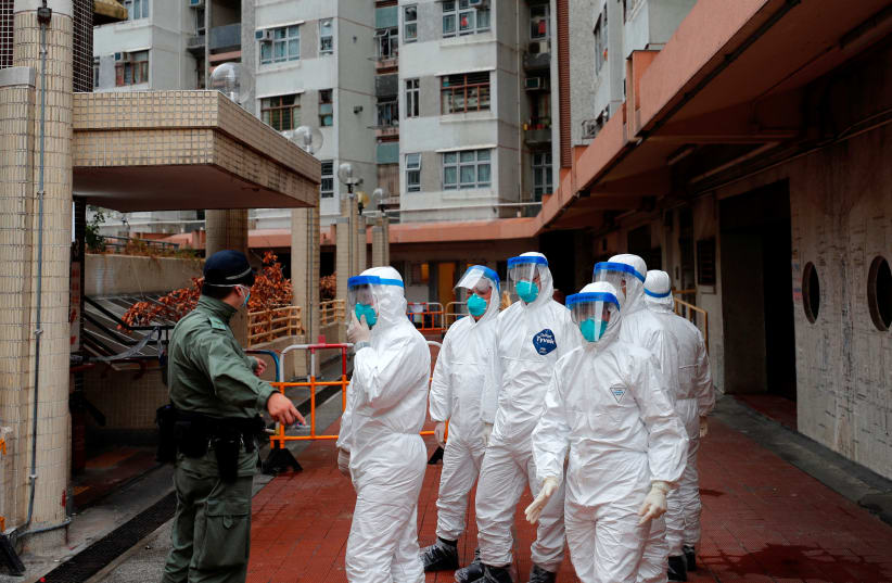 Police in protective gear wait to evacuate residents from a public housing building, following the outbreak of the novel coronavirus, in Hong Kong, China February 11, 2020 (photo credit: REUTERS/TYRONE SIU)