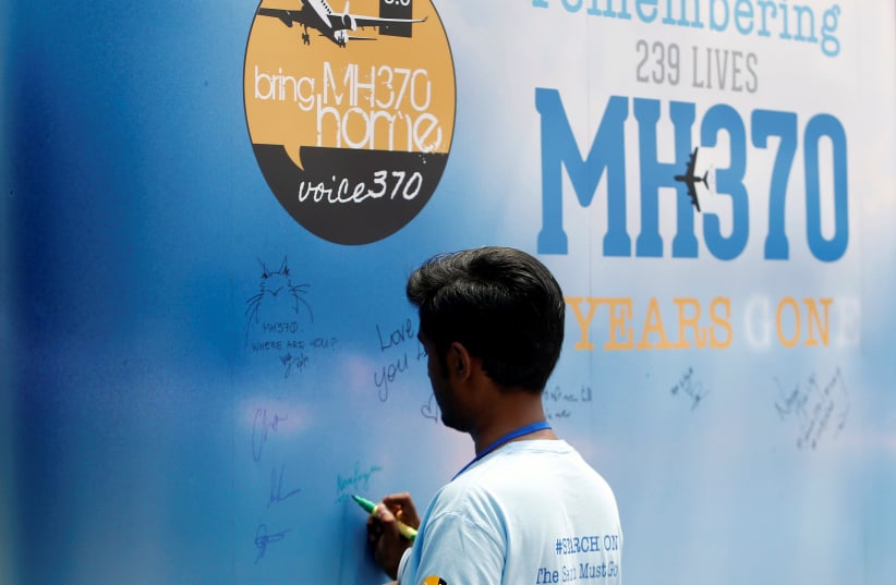 A man writes on a message board for passengers, onboard the missing Malaysia Airlines Flight MH370, during its fifth annual remembrance event in Kuala Lumpur (photo credit: REUTERS)