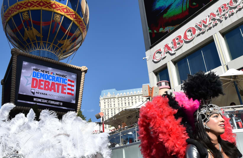 A busker dressed in a showgirl costume walks past the Paris Las Vegas hotel & casino, the site of Wednesday?s Democratic presidential debate, in Las Vegas, Nevada, U.S., February 18, 2020 (photo credit: REUTERS/DAVID BECKER)