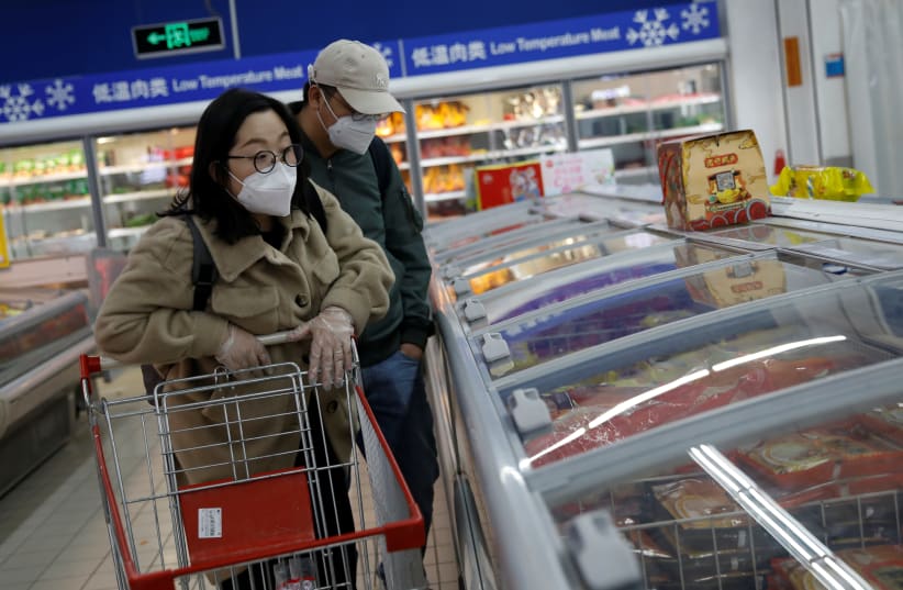People wearing face masks look for products at a supermarket, as the country is hit by an outbreak of the new coronavirus, in Beijing (photo credit: REUTERS)