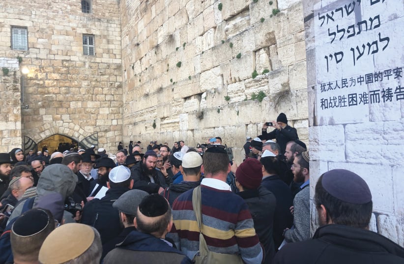AT A MASS prayer service at the Western Wall on Sunday, worshipers pray for those affected by coronavirus. The Hebrew on the poster reads, ‘The People of Israel prays for China.’ (photo credit: YAAKOV LEHMAN)