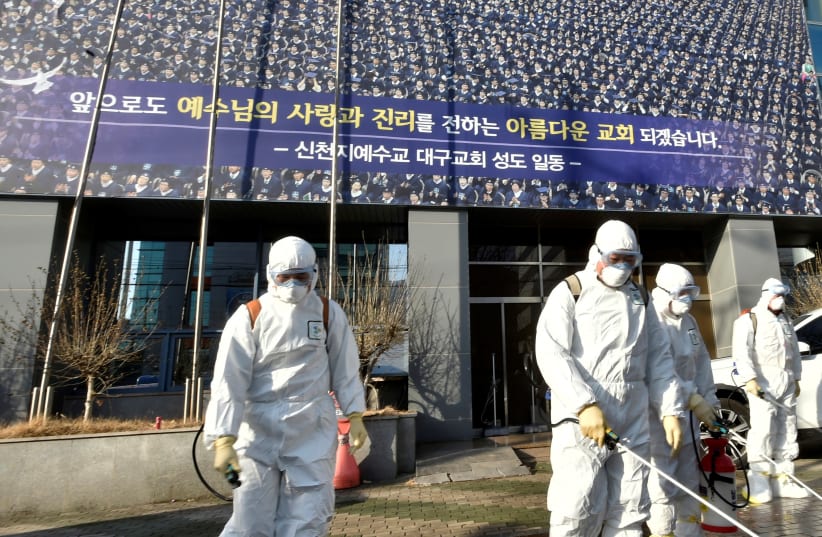 Workers from a disinfection service company sanitize a street in front of a branch of the Shincheonji Church of Jesus the Temple of the Tabernacle of the Testimony where a woman known as "Patient 31" attended a service in Daegu, South Korea, February 19, 2020 (photo credit: YONHAP VIA REUTERS)