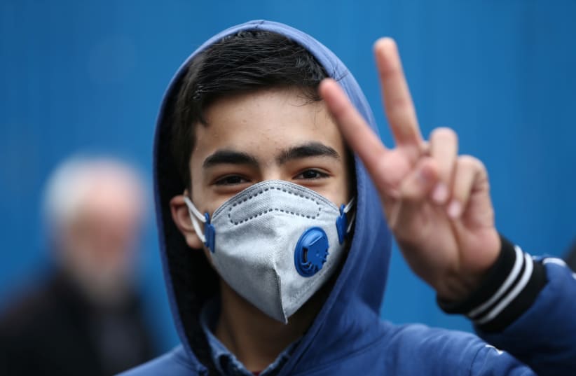 An Iranian boy gestures as he wears protective mask to prevent contracting a coronavirus in Tehran (photo credit: REUTERS)