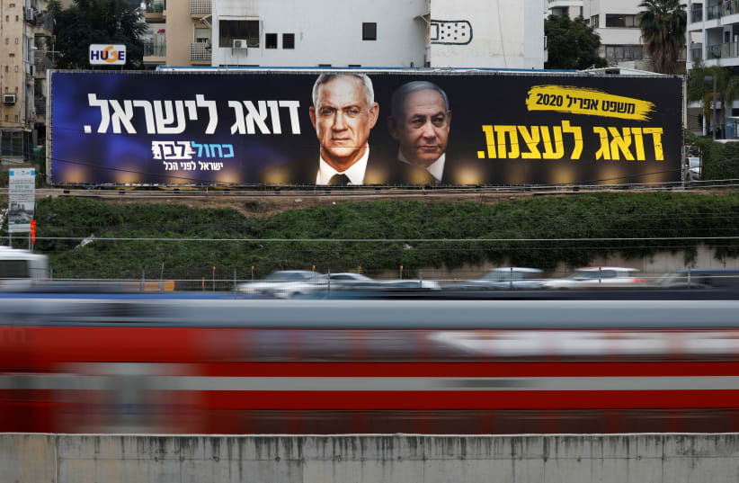 Traffic moves past a Blue and White party election campaign poster, depicting party leader Benny Gantz, and Israeli Prime Minister Benjamin Netanyahu, in Tel Aviv, Israel February 18, 2020 (photo credit: AMIR COHEN/REUTERS)