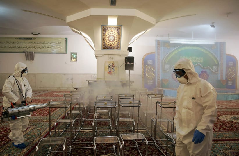 A medical team sprays disinfectant to sanitize Imam Reza's holy shrine, following the coronavirus outbreak, in Mashhad, Iran (photo credit: WANA NEWS AGENCY/REUTERS)