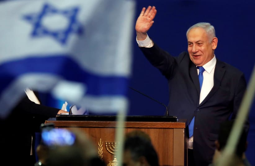 Prime Minister Benjamin Netanyahu waves to supporters following the announcement of exit polls in Israel's election at his Likud party headquarters in Tel Aviv on March 3, 2020.  (photo credit: AMIR COHEN - REUTERS)