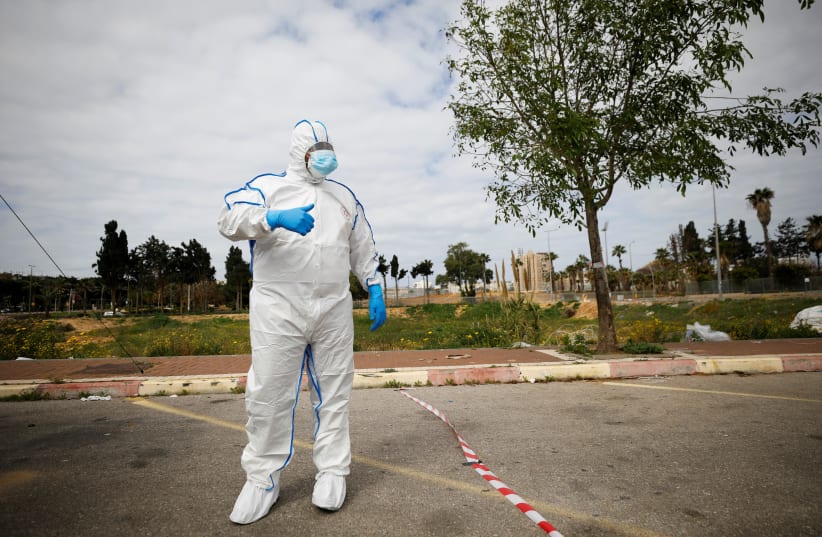 A paramedic wearing a protective suit stands near a special polling station set up by Israel's election committee so Israelis under home-quarantine, such as those who have recently travelled back to Israel from coronavirus hot spots, can vote in Israel's national election, in Ashkelon, Israel March  (photo credit: AMIR COHEN/REUTERS)