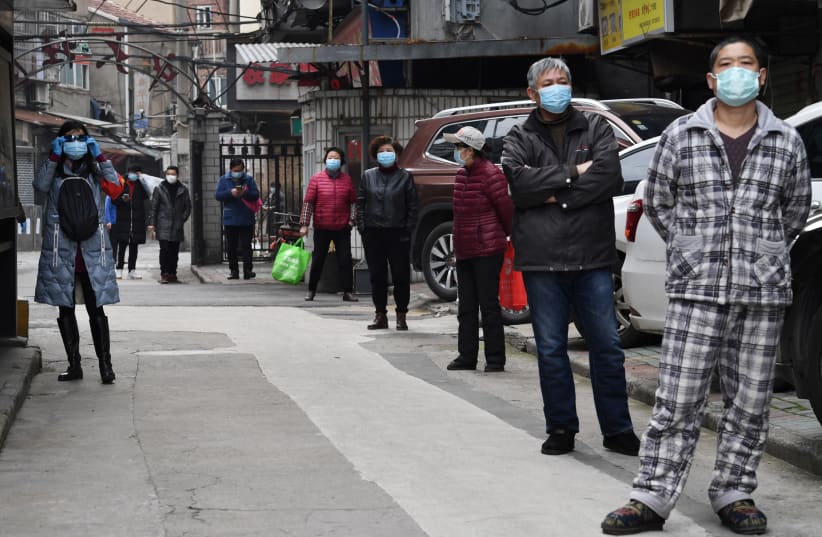 Residents line up to collect vegetables purchased through group orders at a residential area in Wuhan, the epicentre of the novel coronavirus outbreak, Hubei province, China March 5, 2020. (photo credit: REUTERS/STRINGER)