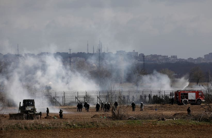 Greek soldiers and riot police officers stand amid clouds of tear gas near Turkey's Pazarkule border crossing, in Kastanies, Greece March 7, 2020 (photo credit: REUTERS/FLORION GOGA)