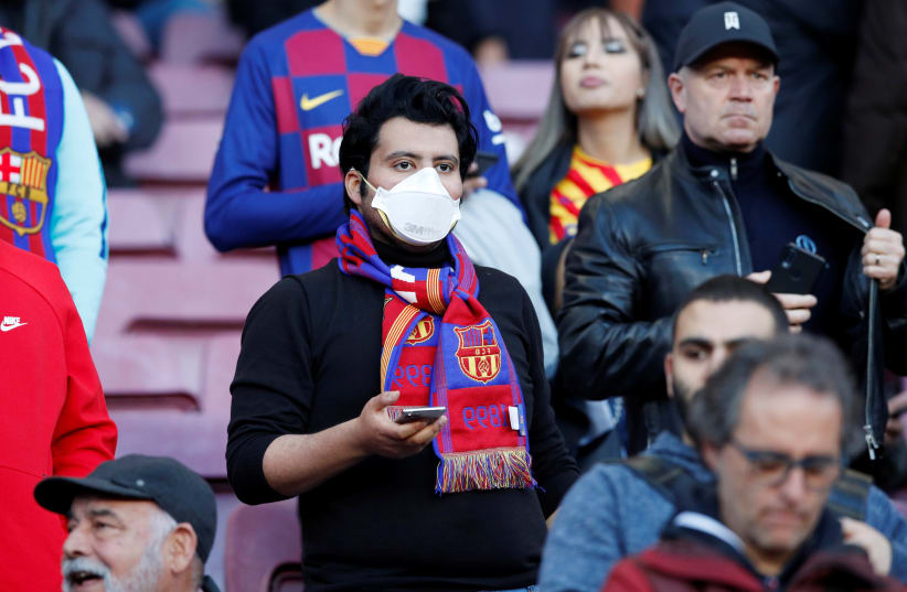 A Barcelona fan wears a mask before the match due to the recent coronavirus outbreak, March 7, 2020 (photo credit: REUTERS/ALBERT GEA)
