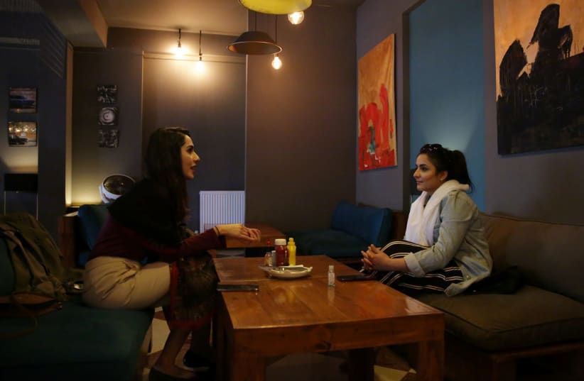 Women chat as they sit at a burger shop in Kabul (photo credit: REUTERS)