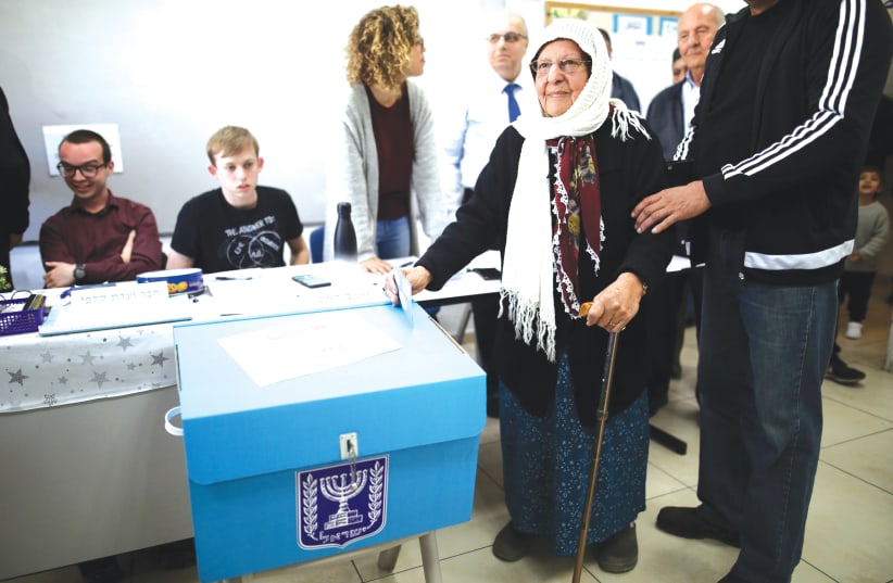 A woman stands next to a ballot box as she prepares to vote in Haifa, last week. (photo credit: AMMAR AWAD/REUTERS)