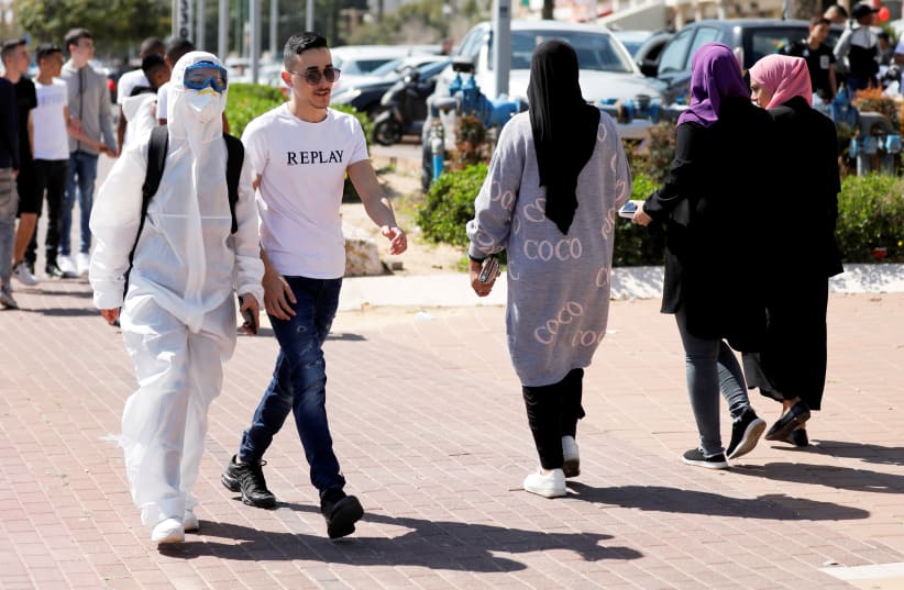 A teenager wears a costume as a reference to coronavirus as school children dress-up marking the Jewish holiday of Purim, a celebration of the Jews' salvation from genocide in ancient Persia, as recounted in the Book of Esther, in Ashkelon, Israel March 8, 2020 (photo credit: REUTERS/AMIR COHEN)