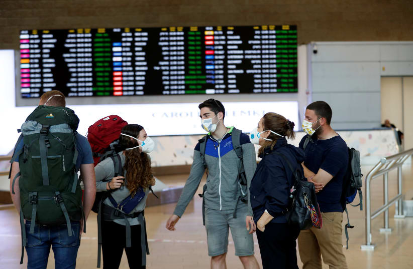 Travelers wearing masks chat in the arrivals terminal after Israel said it will require anyone arriving from overseas to self-quarantine for 14 days as a precaution against the spread of coronavirus, at Ben Gurion International airport in Lod, near Tel Aviv, Israel (photo credit: REUTERS/RONEN ZEVULUN)