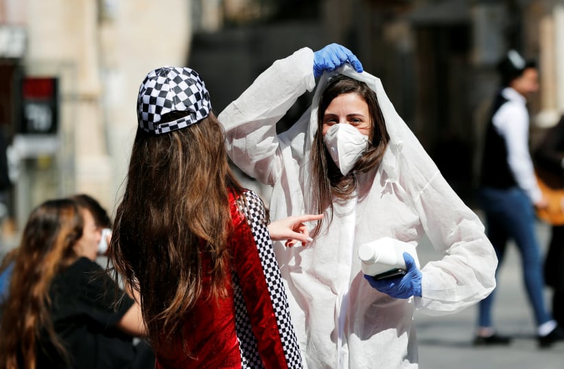 A teenager wears a costume as a reference to the coronavirus during the Jewish holiday of Purim, a celebration of the Jews' salvation from genocide in ancient Persia, as recounted in the Book of Esther. in Jerusalem March 8, 2020 (photo credit: REUTERS/Ronen Zvulun)